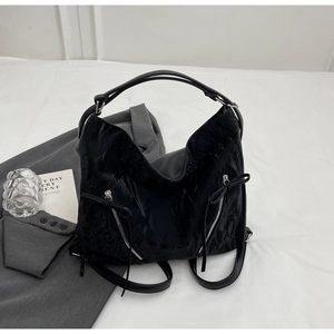 Detail of black pleated tote bag with bow zipper pockets and dual strap versatility