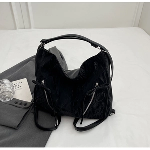 Flat lay of large black crinkled tote bag with silver zippers and stylish bow details