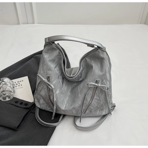 Detail of silver crinkled texture tote with zipper pockets and decorative bow accents