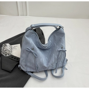 Detailed texture of light blue pleated hobo bag with unique bow-knot zipper pockets