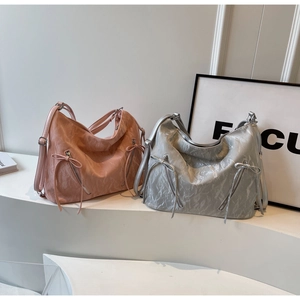 Detailed close-up of pink and silver tote bags featuring bow zippers on a white display stand