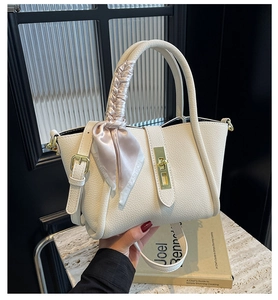 Detail of white lychee leather bucket bag with pink silk scarf handle and gold lock