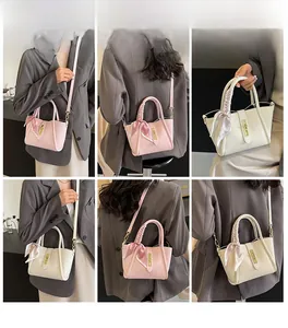Detail of lychee textured tote bag with metal twist lock and silk scarf handle decor