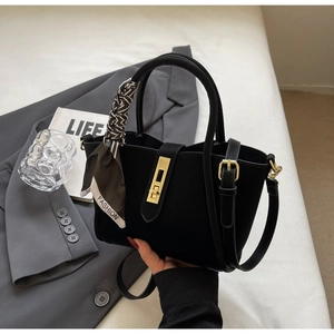 Detail of black leather bucket bag with gold lock and decorative silk scarf handle
