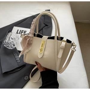 Detail of cream bucket bag with lychee texture leather, gold buckle and fashion scarf wrap