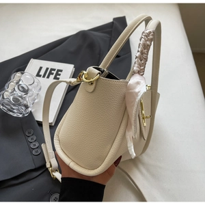 Detail of off-white lychee leather bucket bag with silk scarf handle and golden lock
