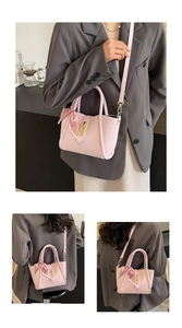 Detail of light pink bucket bag with silk scarf handle and golden twist lock closure