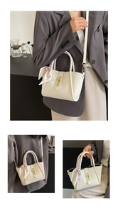 Detail view of cream bucket bag with lychee texture, golden lock, and pink silk scarf