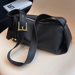 Minimalist black lychee texture leather shoulder bag with adjustable gold buckle on a chair