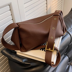 Deep brown lychee leather shoulder bag with gold eyelet strap on white books