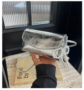 Close-up of silver wrinkled faux leather bag featuring elegant pearl bead charms and handle
