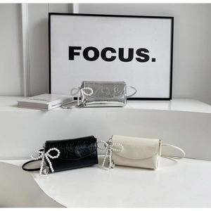 Detailed view of mini crossbody bags with pearl bow charms and heart pendants