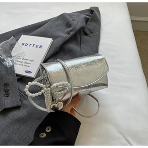 Macro view of silver pleated leather crossbody bag with pearl bow and heart charm