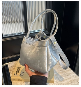 Détail du sac seau métallisé argenté avec double poignées et finitions dorées chic