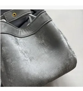 Détail du sac seau argenté avec texture métallisée et œillet doré sur le bord du sac
