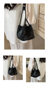 Détail du sac seau noir avec texture en daim et boucles métalliques dorées élégantes