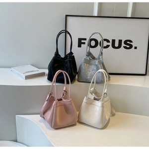 Sacs seaux minimalistes en noir, argent, rose et crème sur un présentoir moderne