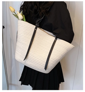 Detail of white woven tote bag with black leather straps and white contrast stitching