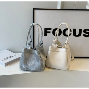 Gros plan de sacs seaux en velours argenté et cuir beige avec poignées fines et plis