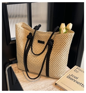 Détail d'un sac cabas en paille tissée beige avec anses en corde noire et intérieur spacieux