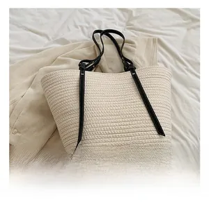 Close-up of beige woven tote bag texture with black leather handles and gold rivets