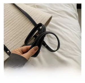 Macro shot of cream woven tote bag with black leather handle and contrast stitching