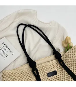Détail du sac cabas tissé ajouré avec bandoulières en corde noire et écusson en cuir