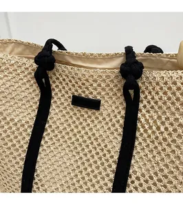 Vue détaillée du sac cabas en paille avec poignées en corde noire et étiquette centrale