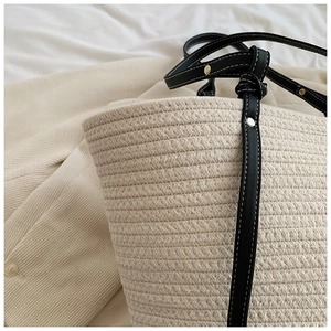 Close-up of woven tote bag texture with leather strap and golden rivet detail