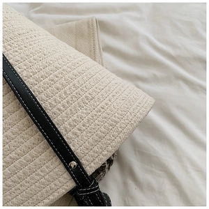 Close-up of woven straw texture with black leather strap and silver rivet details