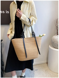 Detail view of large straw tote bag with black leather straps and tulip decor