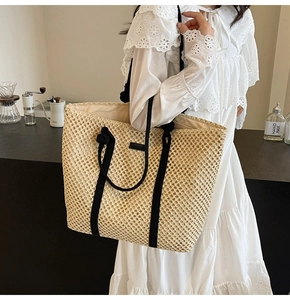 Détail du sac cabas en paille tissé avec anses en corde noire et motif ajouré aéré