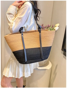 Detail of a large woven tote bag with two-tone design and long black faux leather straps