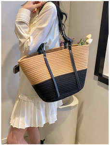 Detail of two-tone woven tote bag with white contrast stitching on black leather straps