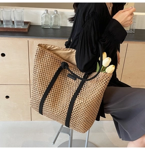 Détail d'un sac cabas en paille tressée avec poignées en corde noire et grand espace