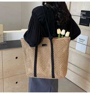 Détail du sac cabas en paille tissé main avec anses en corde noire et logo en cuir