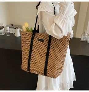 Détail du sac cabas en paille tissée avec anses en corde noire et écusson minimaliste