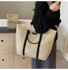 Détail du sac cabas en paille avec poignées en corde noire et écusson logo minimaliste