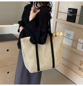 Détail d'un sac cabas en paille tissée avec des sangles noires et des tulipes décoratives