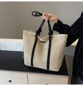 Gros plan détaillé du sac cabas en paille tissée avec poignées en corde noire