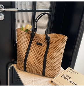 Détail du sac cabas en paille tissée avec poignées en corde noire et texture riche