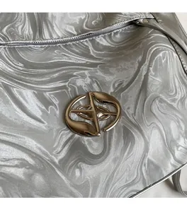 Dettaglio della borsa argento con trama marmorizzata e logo metallico dorato