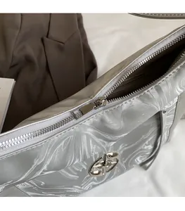 Dettaglio della cerniera scorrevole e logo argento su borsa tote metallizzata