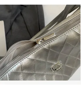 Detail of silver metallic quilted handbag showing smooth zipper and brand buckle