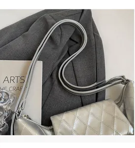 Detail of silver quilted handbag showing the metallic rhombic texture and shoulder strap
