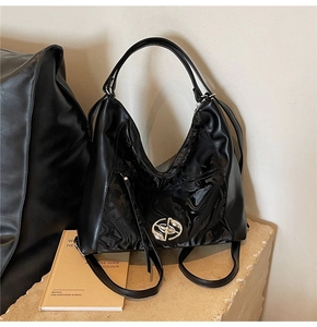 Dettaglio della borsa tote nera con pelle lucida e opaca e fibbia con logo in argento