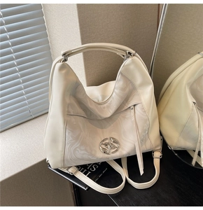 Dettaglio borsa tote color crema con pannello effetto marmo e logo metallico a croce