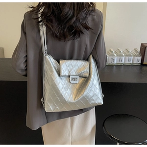 Close-up of metallic silver quilted crossbody bag with turn-lock and zipper details