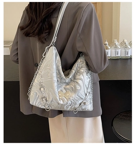 Detail view of silver marbled tote bag with golden butterfly charm and chain strap