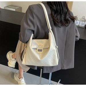 Detail of quilted PU leather texture and silver turn-lock clasp on the white handbag